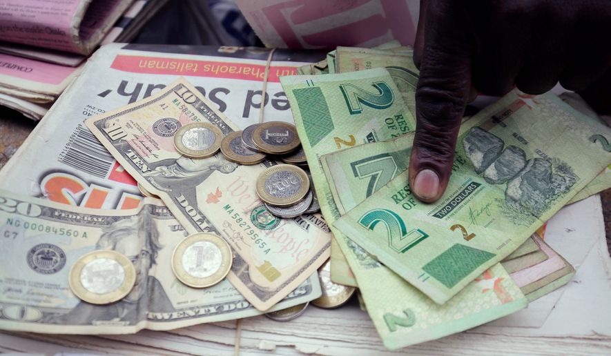 A man counts Zimbabwean dollar notes and coins next to a ten US dollar note on the streets of Harare, Tuesday, June 25, 2019. Zimbabwe President Emmerson Mnangagwa on Tuesday praised the re-introduction of the Zimbabwe dollar as the sole legal tender in the troubled country as a &quot;return to normalcy.&quot; Zimbabwe had for 10 years used the U.S. dollar and other foreign currencies after the Zimbabwean currency was dogged by hyperinflation. (AP Photo/Tsvangirayi Mukwazhi)