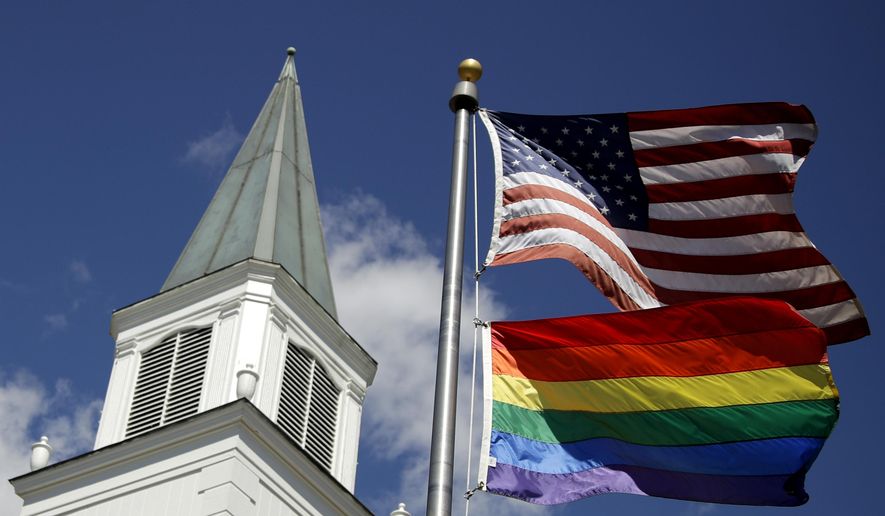 In this April 19, 2019, file photo, a gay pride rainbow flag flies along with the U.S. flag in front of the Asbury United Methodist Church in Prairie Village, Kan. (AP Photo/Charlie Riedel) ** FILE **
