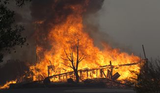 FILE - In this Monday Oct. 9, 2017 file photo flames from a wildfire consume a home, near Napa, Calif. State lawmakers are expected to take up bills on Monday, July 8, 2019, aimed at stabilizing the state&#39;s electric utilities in the face of devastating wildfires caused by their equipment. (AP Photo/Rich Pedroncelli, File)