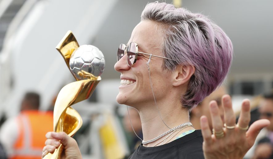 United States women&#39;s soccer team member Megan Rapinoe poses with the Women&#39;s World Cup trophy as she celebrates with teammates after arriving at Newark Liberty International Airport, Monday, July 8, 2019, in Newark, N.J. (AP Photo/Kathy Willens)