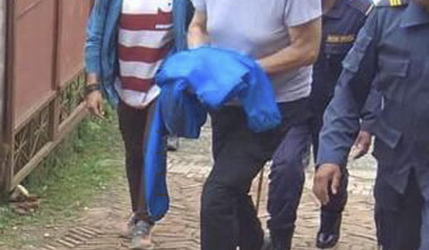 In this Monday, July 8, 2019 photo, Canadian aid worker Peter Dalglish, center wearing red cap, is brought to appear before the Kavre District Court in Nepal. Dalglish was Monday sentenced to nine years in prison in Nepal for sexually abusing two boys who were found at his home. (AP Photo/ Janak Raj Sapkota)