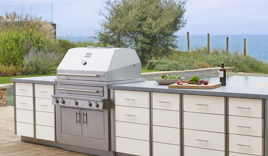 This photo provided by Kalamazoo Outdoor Gourmet of it's Hybrid (charcoal, wood and gas) professional grill and Arcadia series cabinetry is shown at a home in Grand Beach, Mich. Homeowners can add a rolling cart or other freestanding item for storage and food prep space outside. But adding a built-in cooking and storage space around a grill, as seen here, increases the value of a home. (Kalamazoo Outdoor Gourmet via AP)