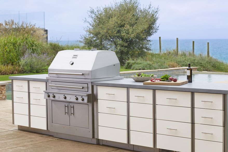 This photo provided by Kalamazoo Outdoor Gourmet of it's Hybrid (charcoal, wood and gas) professional grill and Arcadia series cabinetry is shown at a home in Grand Beach, Mich. Homeowners can add a rolling cart or other freestanding item for storage and food prep space outside. But adding a built-in cooking and storage space around a grill, as seen here, increases the value of a home. (Kalamazoo Outdoor Gourmet via AP)