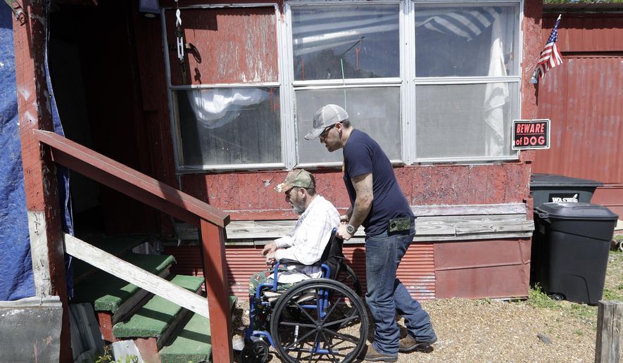 In this April 16, 2019, photo, Johnny Gibbs helps his disabled father, Mike, 65, into their home in Liberty, Tenn. Johnny Gibbs has been trying to get a valid driver's license for 20 years, but he can't afford it. To punish him for high school truancy in 1999, Tennessee suspended his ability to get a license until he turned 21. When Gibbs couldn't pay for traffic violations, he ended up serving jail time and probation. But rather than wiping his fines and allowing him to obtain a valid license, he wound up even more deeply in debt because he had to pay a monthly supervision fee to a private probation company. (AP Photo/Mark Humphrey)