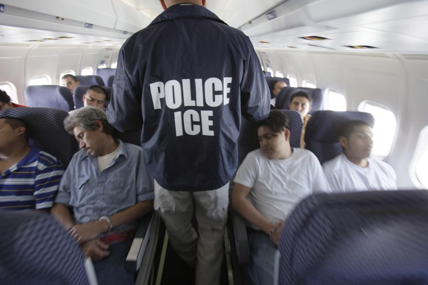 In this May 25, 2010, photo, an Immigration and Customs Enforcement agent walks down the aisle among shackled Mexican immigrants a boarded a U.S. Immigration and Customs Enforcement charter jet for deportation in the air between Chicago, Il. and Harlingen, Texas. (Associated Press) **FILE**