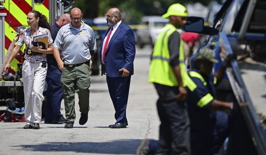 Investigators walk to the crime scene, Tuesday, July 9, 2019, in Cleveland. Police investigating the shooting death of a man in a vacant lot say they also found the bodies of a woman and two children in a nearby house. Authorities aren't saying how the three found inside the house Tuesday died, but they did say the four deaths are connected. (AP Photo/David Dermer)