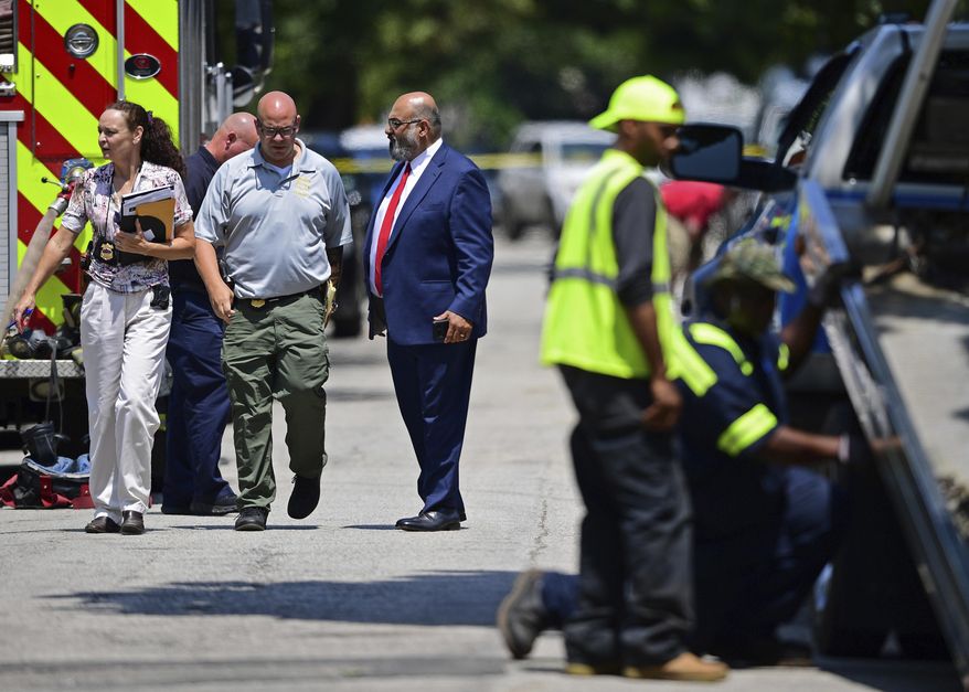 Investigators walk to the crime scene, Tuesday, July 9, 2019, in Cleveland. Police investigating the shooting death of a man in a vacant lot say they also found the bodies of a woman and two children in a nearby house. Authorities aren't saying how the three found inside the house Tuesday died, but they did say the four deaths are connected. (AP Photo/David Dermer)