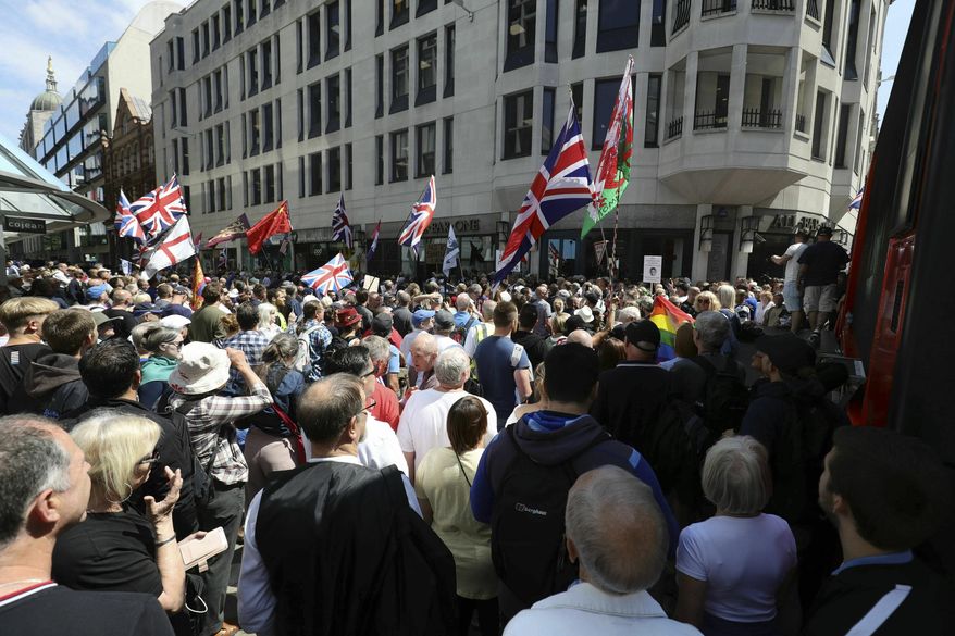 Tommy Robinson supporters stand outside the Old Bailey courthouse in London, Thursday, July 11, 2019. A British judge has sentenced far-right activist Stephen Yaxley-Lennon to a total of nine months in prison for contempt of court. Yaxley-Lennon, who uses the pseudonym Tommy Robinson, was arrested and jailed last year for potentially prejudicing a trial after the Facebook broadcast outside a trial of men accused of sexually abusing teenage girls. (Aaron Chown/PA via AP)