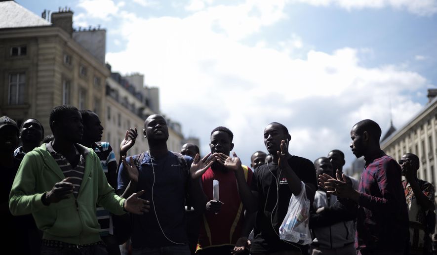 Migrants shout outside the Pantheon monument, where illustrious French figures are buried, in the Latin quarter of Paris, Friday, July 12, 2019. Dozens of migrants invaded the Pantheon. (AP Photo/Kamil Zihnioglu)