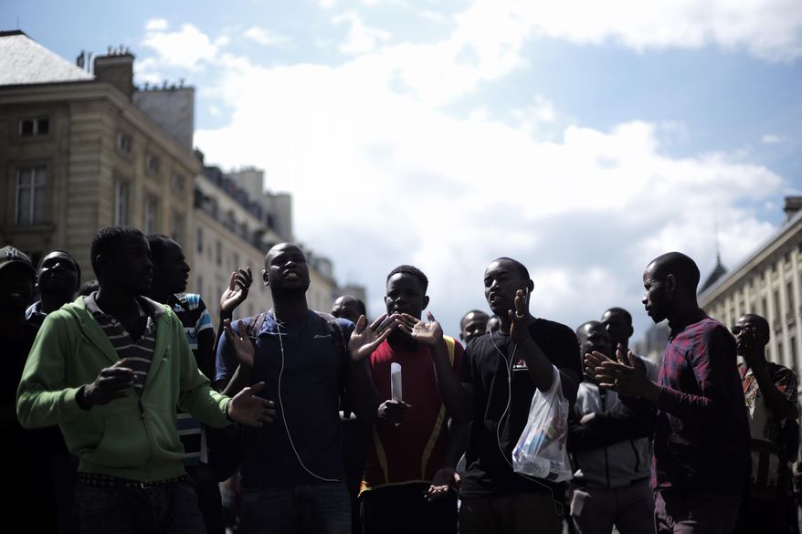Migrants shout outside the Pantheon monument, where illustrious French figures are buried, in the Latin quarter of Paris, Friday, July 12, 2019. Dozens of migrants invaded the Pantheon. (AP Photo/Kamil Zihnioglu)