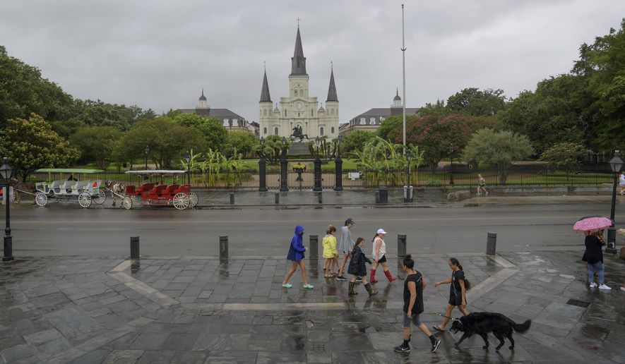 In this file photo from July 12, 2019, people walk past Jackson Square and St. Louis Cathedral in the French Quarter in New Orleans, La. (AP Photo/Matthew Hinton) **FILE**