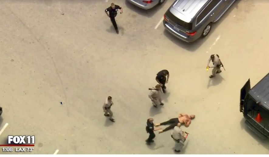 In this image taken from video provided by Fox11 News California Highway Patrol officers approach a shirtless man, lower right, after taking him down with a stun gun after an auto pursuit that began in Orange County ended in a Venice Beach parking lot Friday, July 12, 2019, in Calif. (Fox11 News via AP)