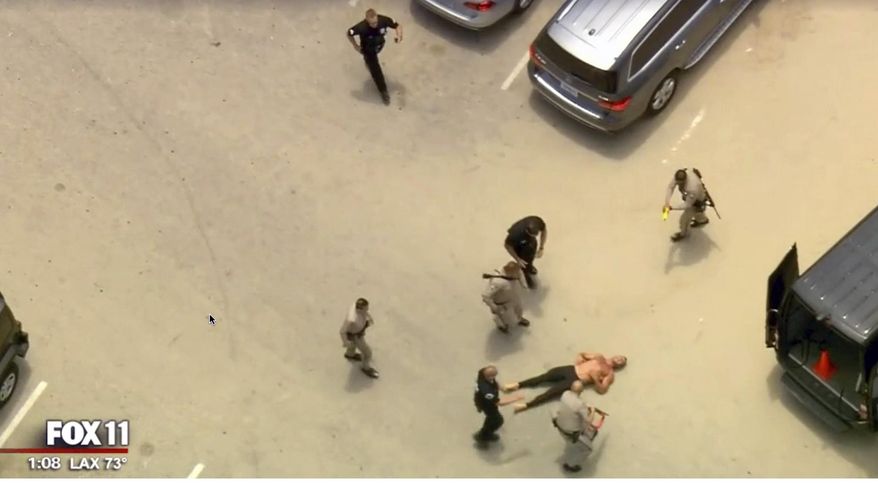 In this image taken from video provided by Fox11 News California Highway Patrol officers approach a shirtless man, lower right, after taking him down with a stun gun after an auto pursuit that began in Orange County ended in a Venice Beach parking lot Friday, July 12, 2019, in Calif. (Fox11 News via AP)