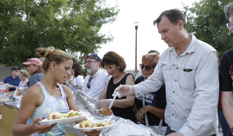 A woman holds out her plate as Rep. Tom Suozzi, D-N.Y., ladles beans onto it during a visit by Democratic members of Congress alongside Team Brownsville Saturday, July 13, 2019, in Matamoros, Mexico. (Denise Cathey/The Brownsville Herald via AP)