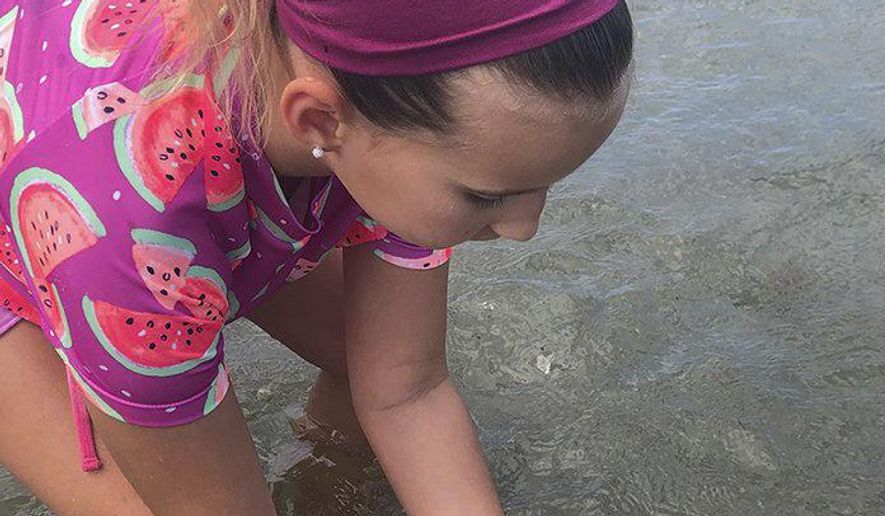 In this Tuesday, July 2, 2019 photo, Samantha Kohl, 10, puts her hands around a baby leatherback turtle in Boca Raton, Fla. Kohl helped save 44 baby leatherbacks when they began hatching in the afternoon sun. (Jaclyn Kohl/Palm Beach Post via AP)