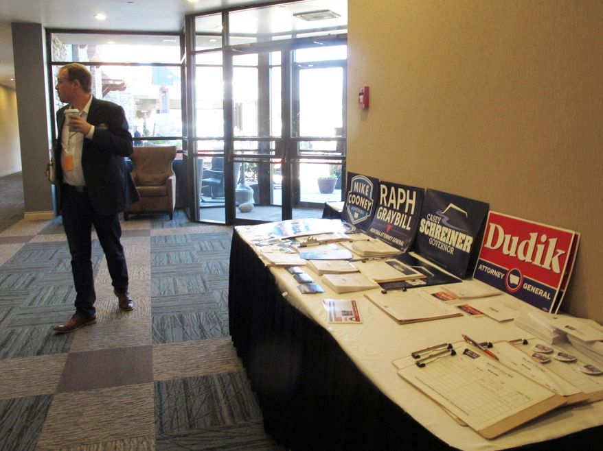 A delegate walks by a table of campaign posters and brochures at the Montana Democratic Party convention in Helena, Montana on Saturday, July 13, 2019. Candidates for governor, U.S. House, U.S. Senate and other statewide offices spoke to delegates from across the state. (AP Photo/Matt Volz)