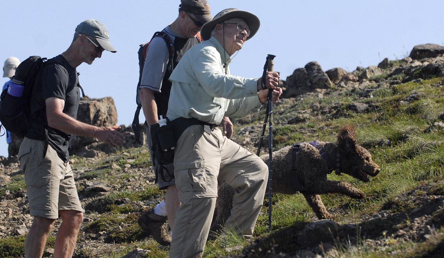 In this July 5, 2019 photo, Doug Wooliver, left, and Steve Wooliver hike alongside their father, George Wooliver, near the top the top of Flattop Mountain in Chugach State Park near Anchorage, Alaska. Anchorage was hidden behind a veil of blue-gray smoke as George Wooliver took in the view of a lifetime from atop Flattop Mountain. Rather than gazing toward the smoke-shrouded city, the 90-year-old birthday boy was instead staring proudly at the three generations of Woolivers who accompanied him on the arduous climb to the top of the 3,510-foot peak on July 5. (Matt Tunseth/Anchorage Daily News via AP)