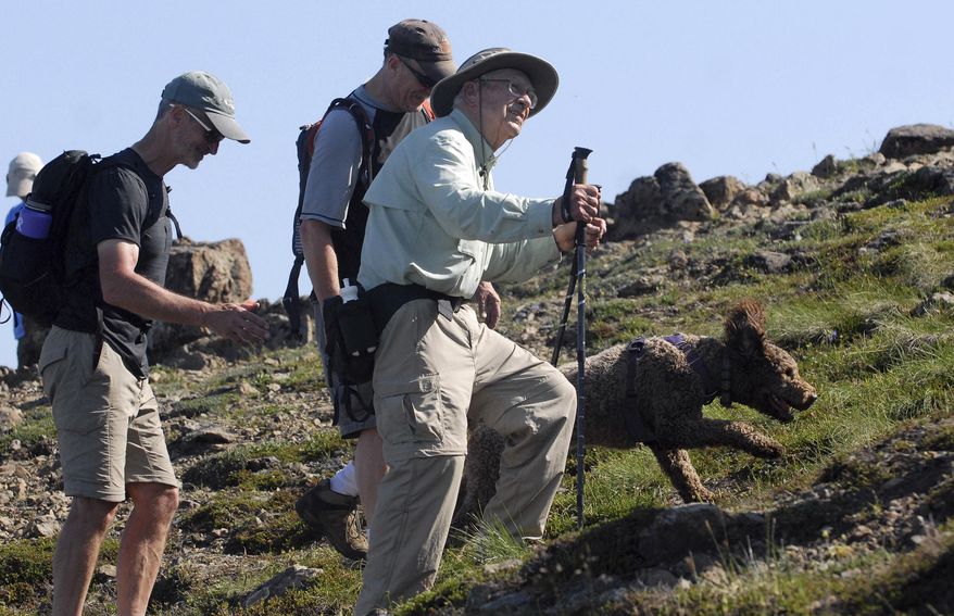 In this July 5, 2019 photo, Doug Wooliver, left, and Steve Wooliver hike alongside their father, George Wooliver, near the top the top of Flattop Mountain in Chugach State Park near Anchorage, Alaska. Anchorage was hidden behind a veil of blue-gray smoke as George Wooliver took in the view of a lifetime from atop Flattop Mountain. Rather than gazing toward the smoke-shrouded city, the 90-year-old birthday boy was instead staring proudly at the three generations of Woolivers who accompanied him on the arduous climb to the top of the 3,510-foot peak on July 5. (Matt Tunseth/Anchorage Daily News via AP)
