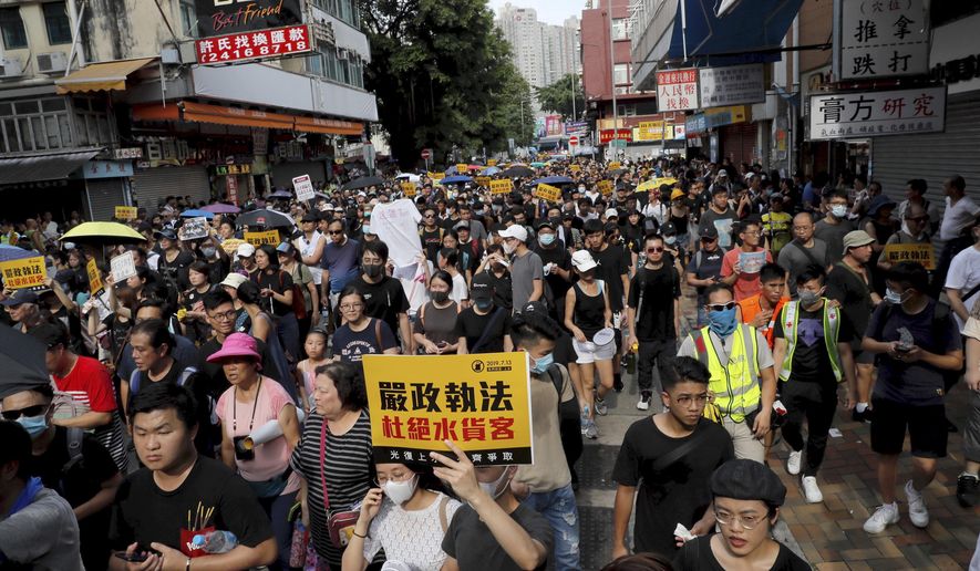 Protesters hold up words that read: "Strict enforcing of law against smugglers of grey goods" in Hong Kong Saturday, July 13, 2019. Several thousand people are marching in Hong Kong against traders from mainland China in what is fast becoming a summer of unrest in the semi-autonomous Chinese territory. (AP Photo/Kin Cheung)