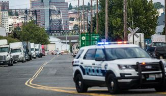 A police officer guards the front of a road block near the Northwest Detention Center, Saturday, July 13, 2019 in Tacoma, Wash. A man armed with a rifle threw incendiary devices at an immigration jail in Washington state early Saturday morning, then was found dead after four police officers arrived and opened fire, authorities said. (Rebekah Welch/The Seattle Times via AP)
