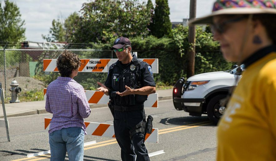 Police Officer Sam Lopez turns away would-be protesters in front of a road block near the Northwest Detention Center, Saturday July 13, 2019 in Tacoma, Wash. A man armed with a rifle threw incendiary devices at an immigration jail in Washington state early Saturday morning, then was found dead after four police officers arrived and opened fire, authorities said. (Rebekah Welch/The Seattle Times via AP)
