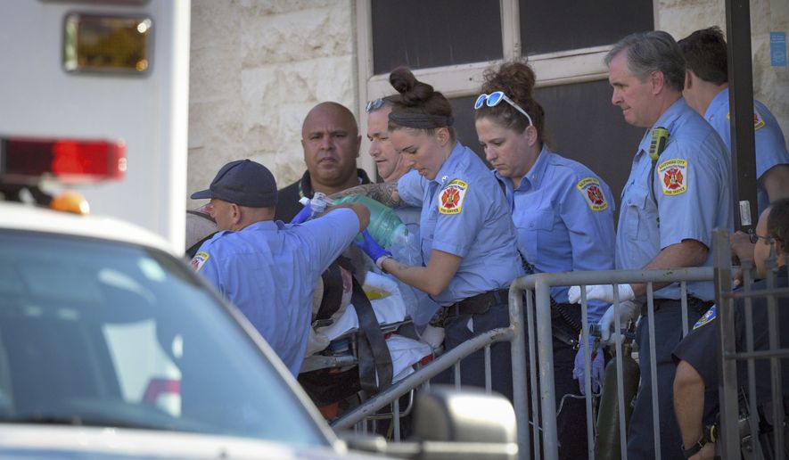 Baltimore Fire Dept. paramedics transport a patient from the Man Alive drug treatment center on Maryland Avenue Monday, July 15, 2019 shortly after a shooting. At least two people are dead and a police sergeant and a woman are injured following a shooting at a methadone clinic in Baltimore, police said Monday. (Jerry Jackson/The Baltimore Sun via AP)