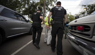 In this July 8, 2019, photo, a U.S. Immigration and Customs Enforcement (ICE) officers escort a man in handcuffs during an operation in Escondido, Calif. The carefully orchestrated arrest last week in this San Diego suburb illustrates how President Donald Trump&#39;s pledge to start deporting millions of people in the country illegally is virtually impossible with ICE&#39;s budget and its method of picking people up. (AP Photo/Gregory Bull) **FILE**