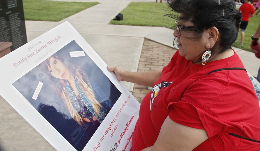 FILE - In this Friday, June 14, 2019, file photo, Carmen Thompson, of El Reno, Okla., looks over a poster of her niece Emily Morgan who was murdered in 2016, before the start of a march to call for justice for missing and murdered indigenous women at the Cheyenne and Arapaho Tribes of Oklahoma in Concho, Okla. U.S. Senate staffers say officials missed a second deadline on July 8 to offer input on bills on Native American safety, and only one department has since provided “partial comment.” (AP Photo/Sue Ogrocki, File)