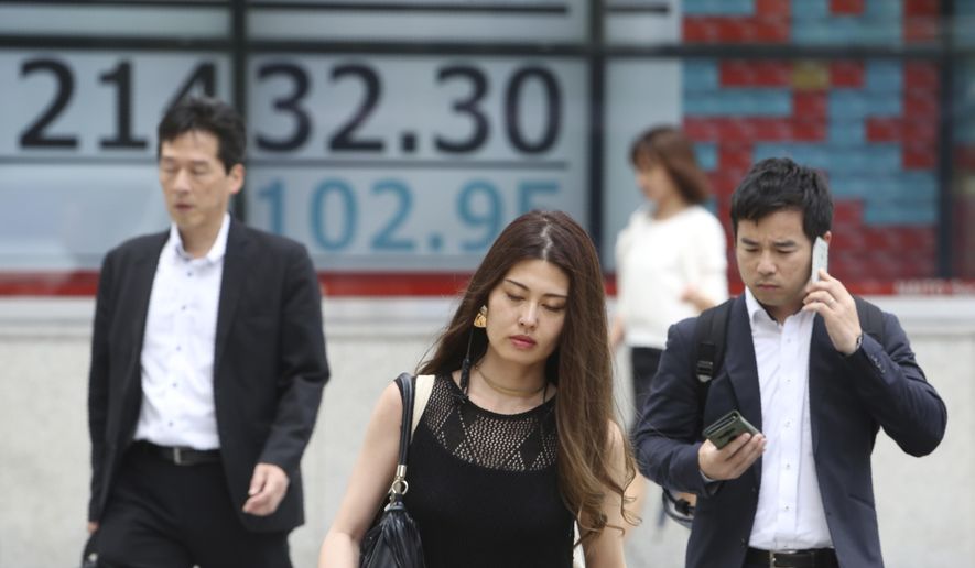 People walk by an electronic stock board of a securities firm in Tokyo, Wednesday, July 17, 2019. Asian stocks were mixed Wednesday as Wall Street ended a five-day winning streak after the first big round of corporate earnings reports. (AP Photo/Koji Sasahara)