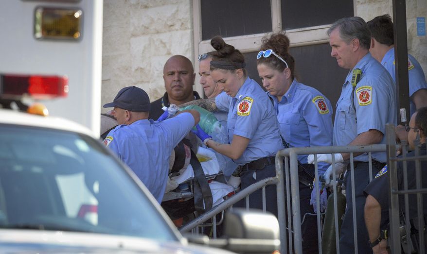 Baltimore Fire Dept. paramedics transport a patient from the Man Alive drug treatment center on Maryland Avenue Monday, July 15, 2019 shortly after a shooting. At least two people are dead and a police sergeant and a woman are injured following a shooting at a methadone clinic in Baltimore, police said Monday. (Jerry Jackson/The Baltimore Sun via AP)