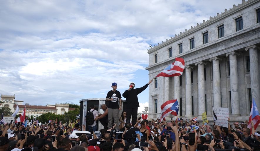 Puerto Rican rapper Rene Juan Perez known by his stage name Residente and Benito Antonio Martinez Ocasio, known by his stage name Bad Bunny, warm up the crowd in front of the Puerto Rican Capitol, before a protest march against governor Ricardo Rosello, in San Juan, Puerto Rico, Wednesday, July 17, 2019. Protesters are demanding Rossell&amp;#243; step down for his involvement in a private chat in which he used profanities to describe an ex-New York City councilwoman and a federal control board overseeing the island&#x27;s finance. (AP Photo/Dennis M. Rivera Pichardo)
