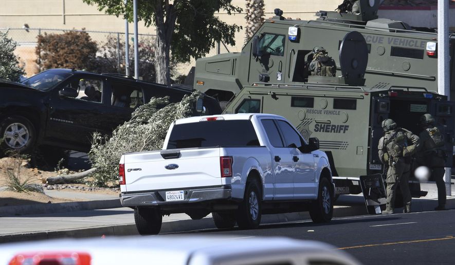 A San Bernardino County Sheriff's SWAT team surrounds a car involved in a shooting with deputies in Victorville, Calif., on Wednesday July 17, 2019. Authorities say a deputy has been hurt and a suspected gunman captured after a gunfire-punctuated confrontation in inland Southern California. (James Quigg/The Daily Press via AP)
