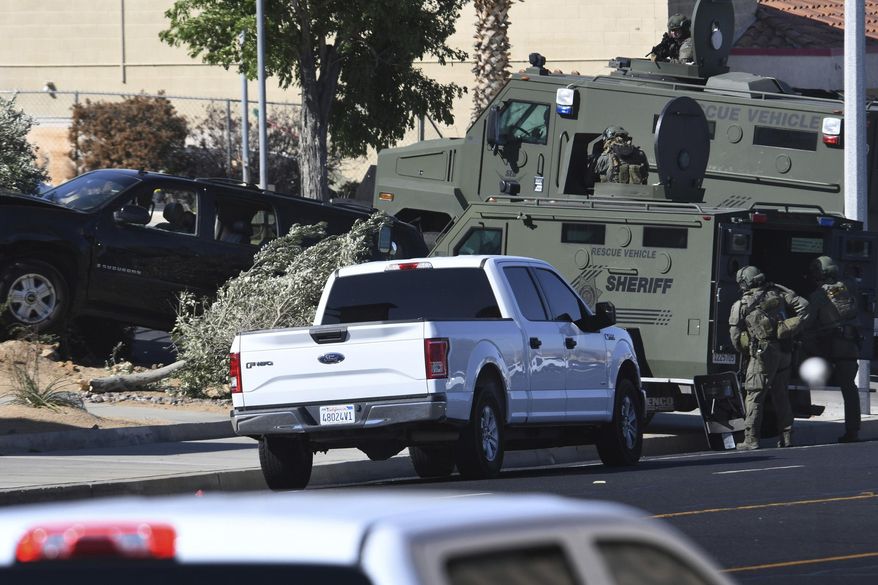 A San Bernardino County Sheriff's SWAT team surrounds a car involved in a shooting with deputies in Victorville, Calif., on Wednesday July 17, 2019. Authorities say a deputy has been hurt and a suspected gunman captured after a gunfire-punctuated confrontation in inland Southern California. (James Quigg/The Daily Press via AP)