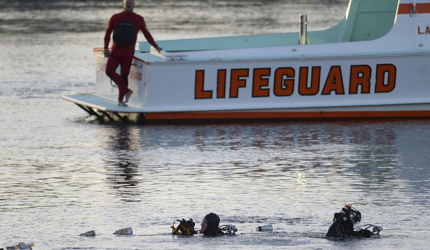 FILE - In this April 9, 2015 file photo, divers emerge from the water as debris believed to be from a car floats to the surface where a car went off a pier and into the water in Los Angeles' San Pedro harbor district. Los Angeles prosecutors have charged an Egyptian father with murder after he allegedly drove his family off a pier, killing his two autistic sons. The district attorney's office said Wednesday, July 17, 2019 there's a special circumstance allegation that the killings were carried out by Ali Elmezayen for financial gain. (Steve McCrank/The Orange County Register via AP, File)