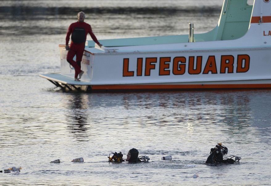 FILE - In this April 9, 2015 file photo, divers emerge from the water as debris believed to be from a car floats to the surface where a car went off a pier and into the water in Los Angeles' San Pedro harbor district. Los Angeles prosecutors have charged an Egyptian father with murder after he allegedly drove his family off a pier, killing his two autistic sons. The district attorney's office said Wednesday, July 17, 2019 there's a special circumstance allegation that the killings were carried out by Ali Elmezayen for financial gain. (Steve McCrank/The Orange County Register via AP, File)