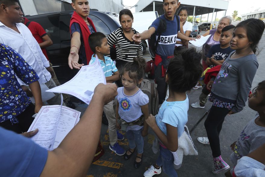Pastor Aaron Mendes hands out documents to migrants before they enter the immigration office on the Mexican side of the border, before they are escorted across to apply for asylum on the United States side, in Nuevo Laredo, Mexico, Wednesday, July 17, 2019. Asylum-seekers grappled to understand what a new U.S. policy that all but eliminates refugee claims by Central Americans and many others meant for their bids to find a better life in America amid a chaos of rumors, confusion and fear. (AP Photo/Marco Ugarte)