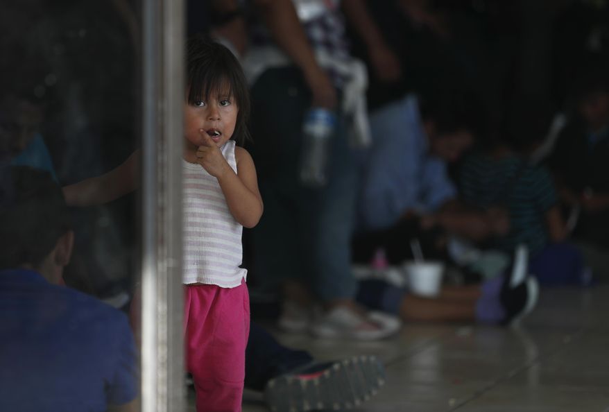 A migrant child looks at the camera while her parents wait at an immigration center on the International Bridge 1, in Nuevo Laredo, Mexico, Tuesday, July 16, 2019. A U.S. policy to make asylum seekers wait in Mexico while their cases wind through clogged U.S. immigration courts has also expanded to the violent city of Nuevo Laredo. (AP Photo/Marco Ugarte)