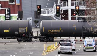 FILE - In this Feb. 13, 2018, file photo, automobile traffic waits at a train crossing as train cars that carry oil are pulled through downtown Seattle. Attorneys general for North Dakota and Montana have petitioned the Trump administration Wednesday, July 17, 2019, to overrule a Washington state law that imposes safety restrictions on oil shipped by rail from the Northern Plains. (AP Photo/Elaine Thompson, File)