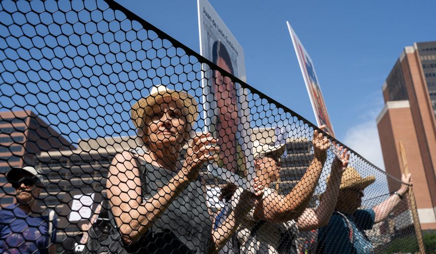 Shelly Yanoff from "Elder Witness" pens herself inside a makeshift detention center holding a poster of a deceased child to dramatize the stories of children who have died in U.S. custody during an event held at Independence Mall, in Philadelphia. (Anthony Pezzotti/The Philadelphia Inquirer via AP)