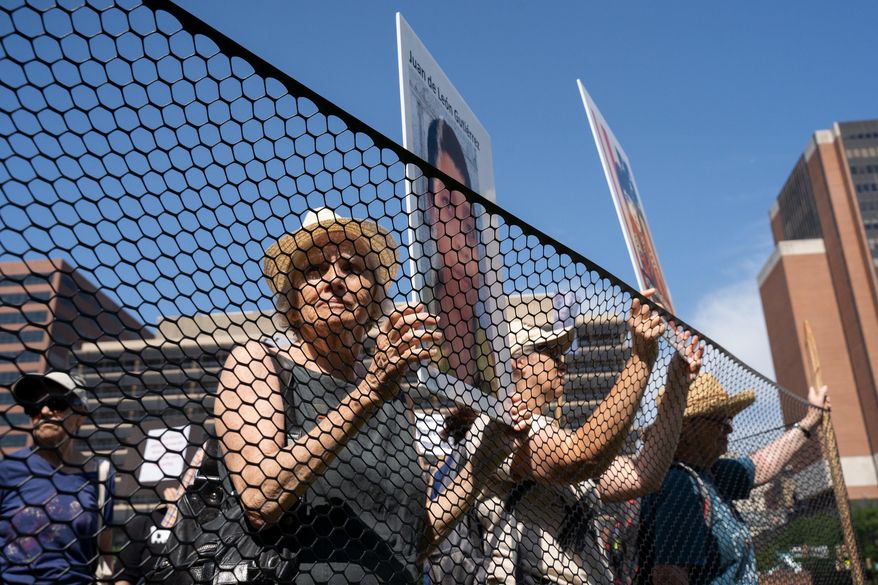 Shelly Yanoff from "Elder Witness" pens herself inside a makeshift detention center holding a poster of a deceased child to dramatize the stories of children who have died in U.S. custody during an event held at Independence Mall, in Philadelphia. (Anthony Pezzotti/The Philadelphia Inquirer via AP)