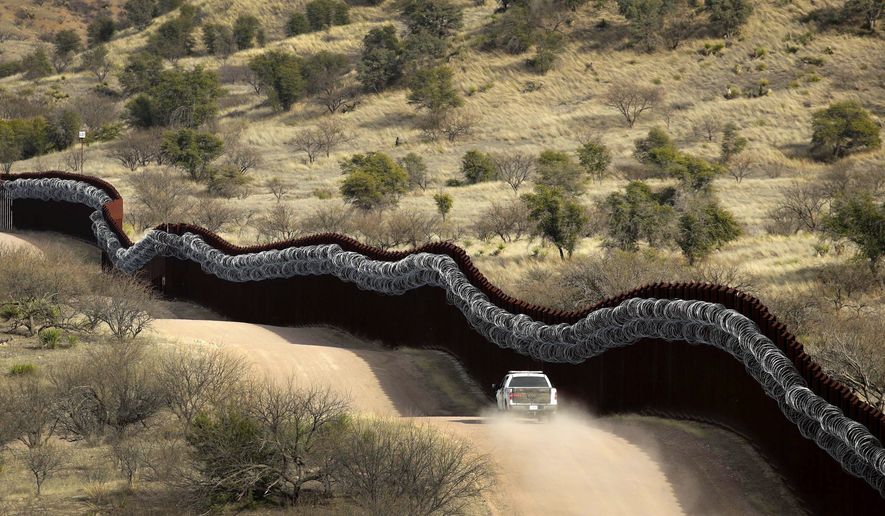 A Customs and Border Control agent patrols the defining line between the U.S. and Mexico near Nogales, Arizona, — far from the noise of immigration arguments on Capitol Hill and elsewhere. (Associated Press)