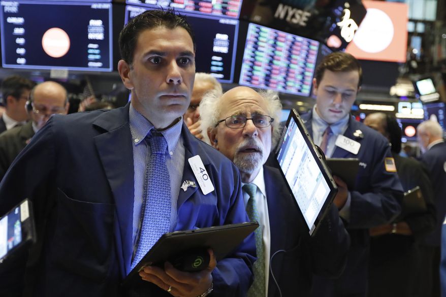 Traders Craig Spector, left, and Peter Tuchman, center, work on the floor of the New York Stock Exchange, Thursday, July 18, 2019. U.S. stocks moved lower in early trading on Wall Street Thursday after Netflix reported a slump in new subscribers and dragged down communications companies. (AP Photo/Richard Drew)