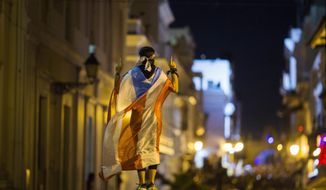 A demonstrator with a Puerto Rican flag reacts during clashes in San Juan, Puerto Rico, Wednesday, July 17, 2019. Thousands of people marched to the governor&#39;s residence in San Juan on Wednesday chanting demands for Gov. Ricardo Rossello to resign after the leak of online chats that show him making misogynistic slurs and mocking his constituents. (AP Photo/Dennis M. Rivera Pichardo)