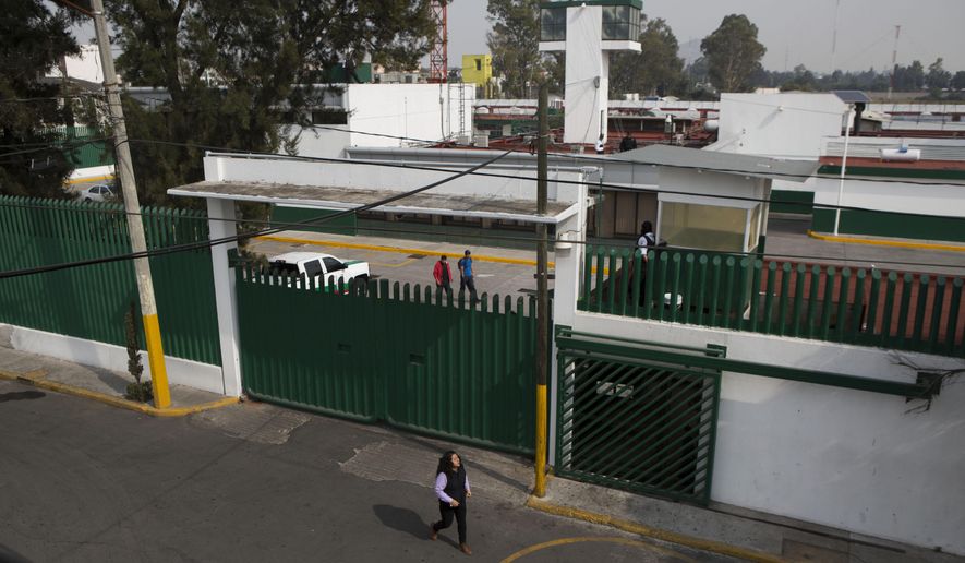 FILE - In this Dec. 31, 2015 file photo, a woman walks past Las Agujas immigration detention center in Mexico City. Mexico’s National Human Rights Commission said on Friday, July 19, 2019, that the migrant detention center in the capital suffers from bedbugs, bad food and overcrowding. The governmental commission said the issues were pointed out more than a year ago and still haven’t been resolved. (AP Photo/Rebecca Blackwell, File)