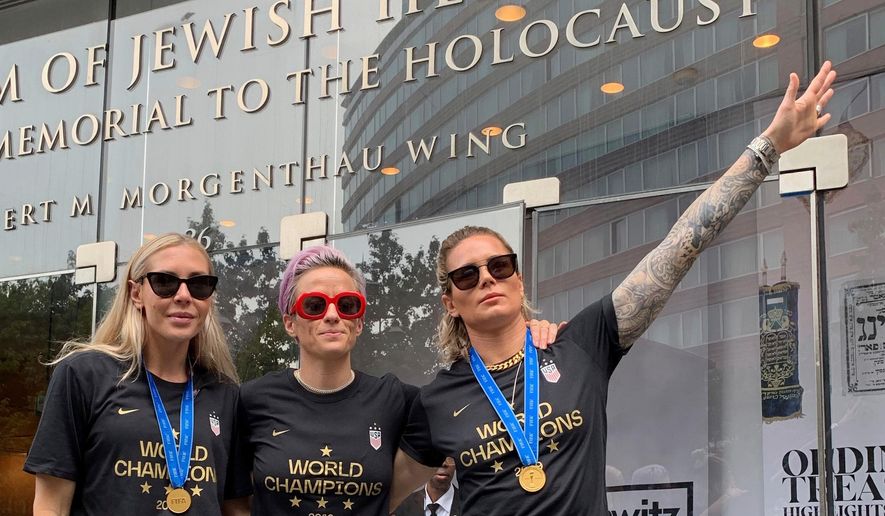 In this Wednesday, July 10, 2019 photo provided by Jeff Simmons, U.S. women's soccer player Ashlyn Harris raises her left arm next to her teammates, Allie Long and Megan Rapinoe, outside the Museum of Jewish Heritage before a victory parade in New York City, to celebrate the team's Women's World Cup title. On Friday, July 19, 2019, The Associated Press reported on stories circulating online incorrectly asserting that Harris is giving a Nazi salute. This photo was made after the museum hosted a breakfast for players before the ticker-tape parade, said Simmons, the executive vice president for Anat Gerstein, Inc., a public relations firm that works with the museum. (Jeff Simmons via AP)