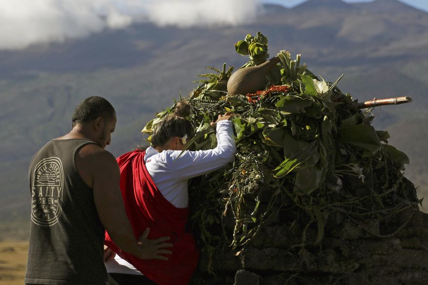 In this Sunday, July 14, 2019, file photo, Native Hawaiian activists pray at the base of Hawaii's Mauna Kea, background. For activists who say they're protecting Mauna Kea, the fight against the proposed Thirty Meter Telescope is a boiling point in Hawaiian history: the overthrow on the Hawaiian kingdom, battles over land, water and development and questions about how the islands should be governed. (AP Photo/Caleb Jones, File)