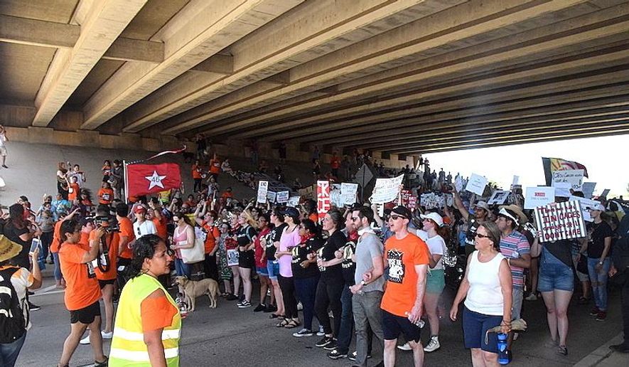 Protesters march to the Rogers Lane overpass after demonstrating at the North Sheridan Road gates of Fort Sill Saturday, July 20, 2019 in Lawton, Okla. More than 100 demonstrators protested in withering heat outside of the Oklahoma Army base against the Trump administration's plans to detain migrant children there. (Scott Rains /The Lawton Constitution via AP)