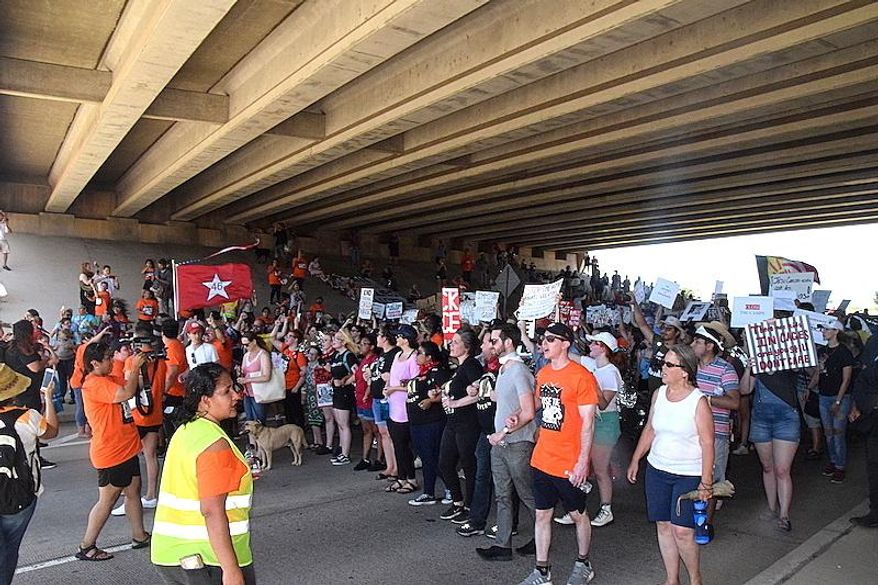 Protesters march to the Rogers Lane overpass after demonstrating at the North Sheridan Road gates of Fort Sill Saturday, July 20, 2019 in Lawton, Okla. More than 100 demonstrators protested in withering heat outside of the Oklahoma Army base against the Trump administration's plans to detain migrant children there. (Scott Rains /The Lawton Constitution via AP)