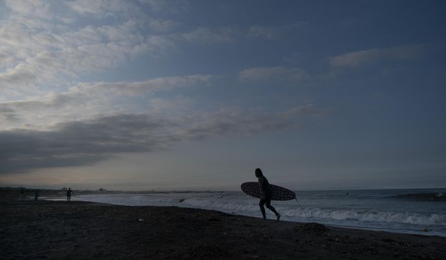 In this Wednesday, July 17, 2019, photo, a surfer walks out of the ocean at Taito Beach located next to Tsurigasaki, a venue for surfing at the Tokyo 2020 Olympics, in Isumi, Chiba prefecture, east of Tokyo. As one of five new sports being added to the program for 2020 Tokyo Olympics, surfing is arguably the most glamorous and is sure to bring a new dimension as the IOC seeks a younger audience. (AP Photo/Jae C. Hong) **FILE**