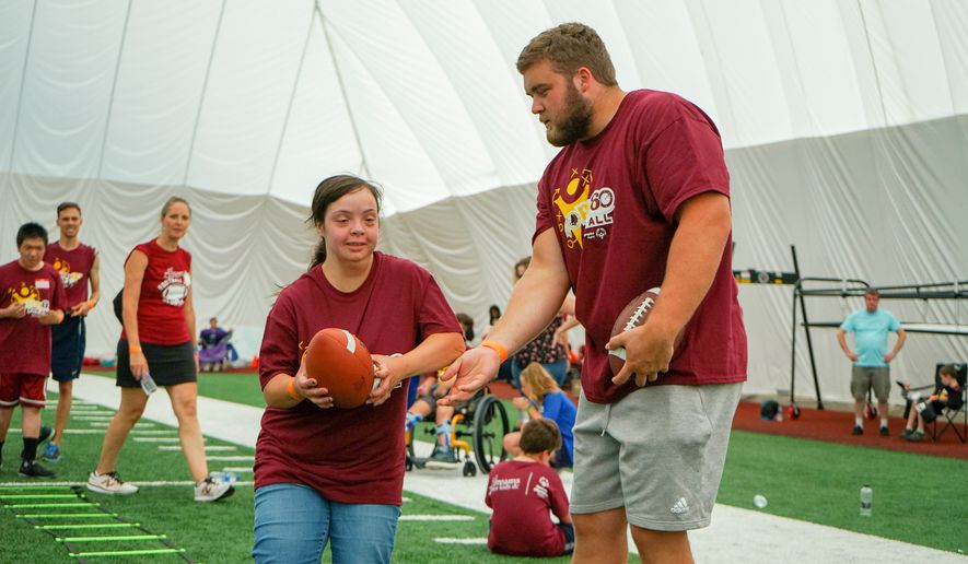 Redskins rookie guard Wes Martin hands off a football at Washington&#39;s &quot;Special Olympics and Dreams for Kids Flag Football Kickoff&quot; on Sunday, July 21 at the team&#39;s indoor facility in Ashburn, Virginia. (Photo courtesy of Stephanie Choi/Dreams for Kids) 